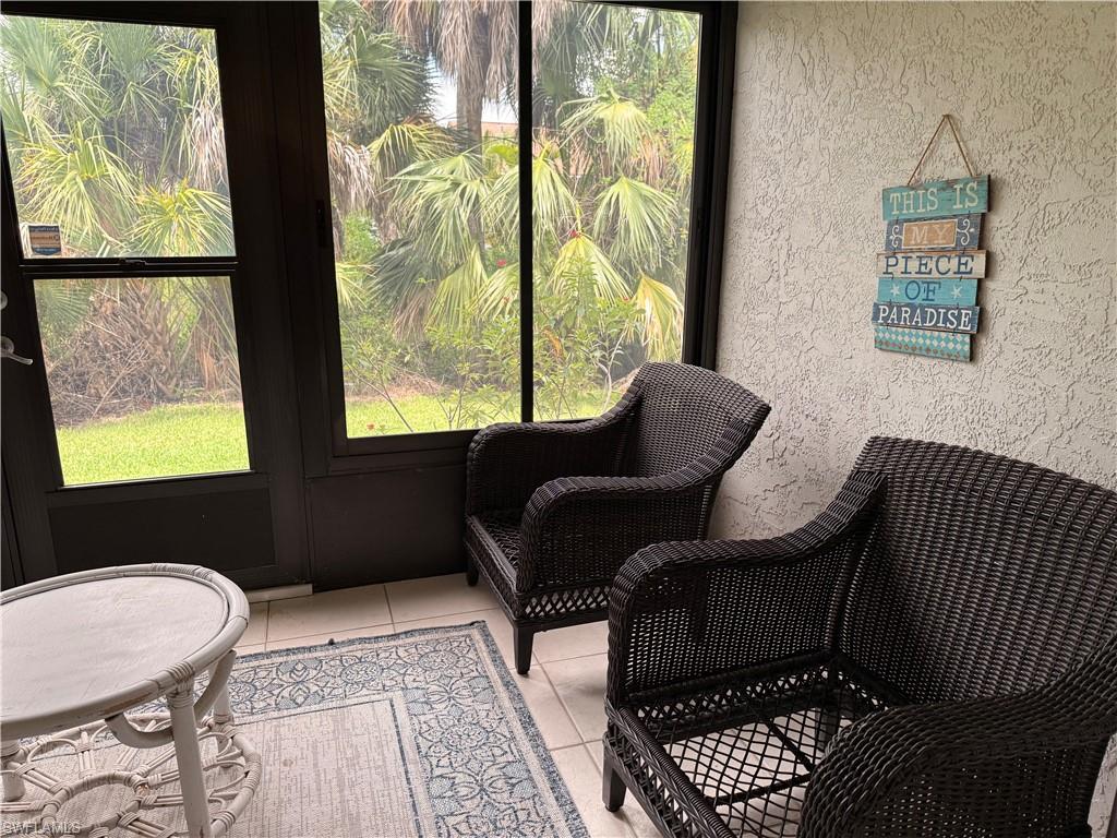 Screened enclosure featuring a tile floor, textured wall finish, and exterior views of tropical foliage