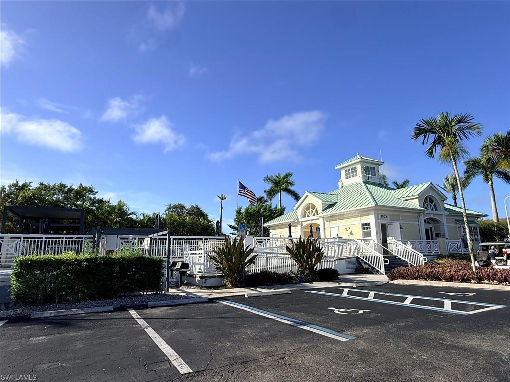 Building with a light-colored exterior, green metal roof, a cupola, and white railings