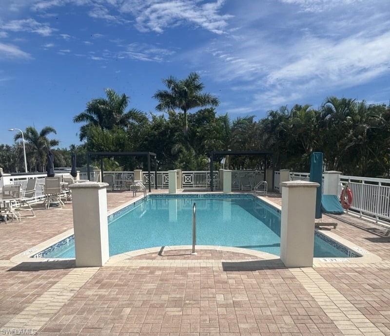 Rectangular swimming pool with a mosaic tile border, surrounded by a paver deck