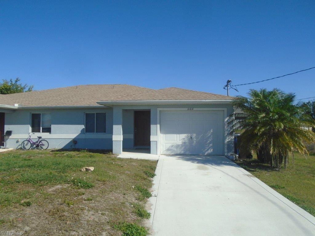 Ranch-style home featuring a garage, driveway, stucco siding, and a front lawn