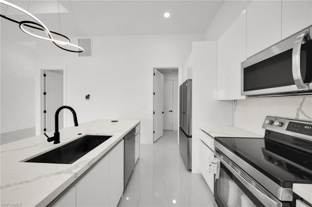 Contemporary kitchen featuring an oversized island with a black sink and matte black faucet