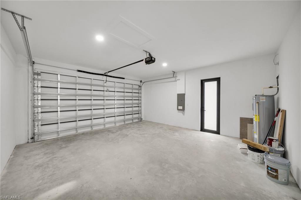 Spacious garage featuring a roll-up door, concrete flooring, recessed lighting, and a side access door
