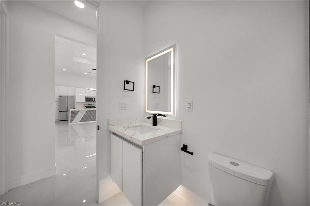Modern vanity with a white countertop and integrated sink, illuminated mirror, and matte black fixtures