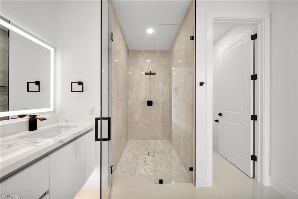 Contemporary bathroom featuring a frameless glass shower enclosure with neutral-toned tiled walls and a pebble-style floor