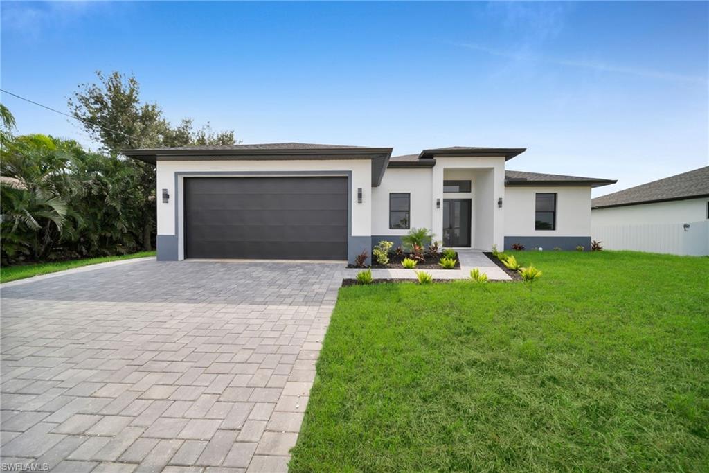 Contemporary stucco exterior featuring a dark gray garage door and a paver driveway