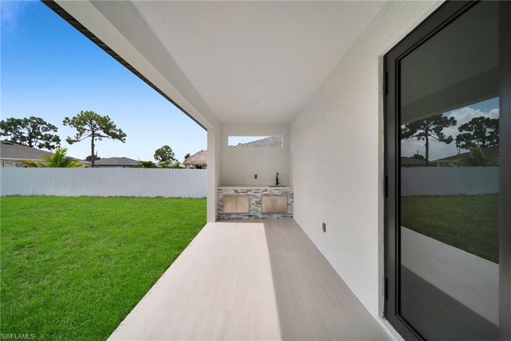 Covered patio featuring an outdoor kitchen with stone-finish countertop, under-mount sink, and stainless steel cabinets