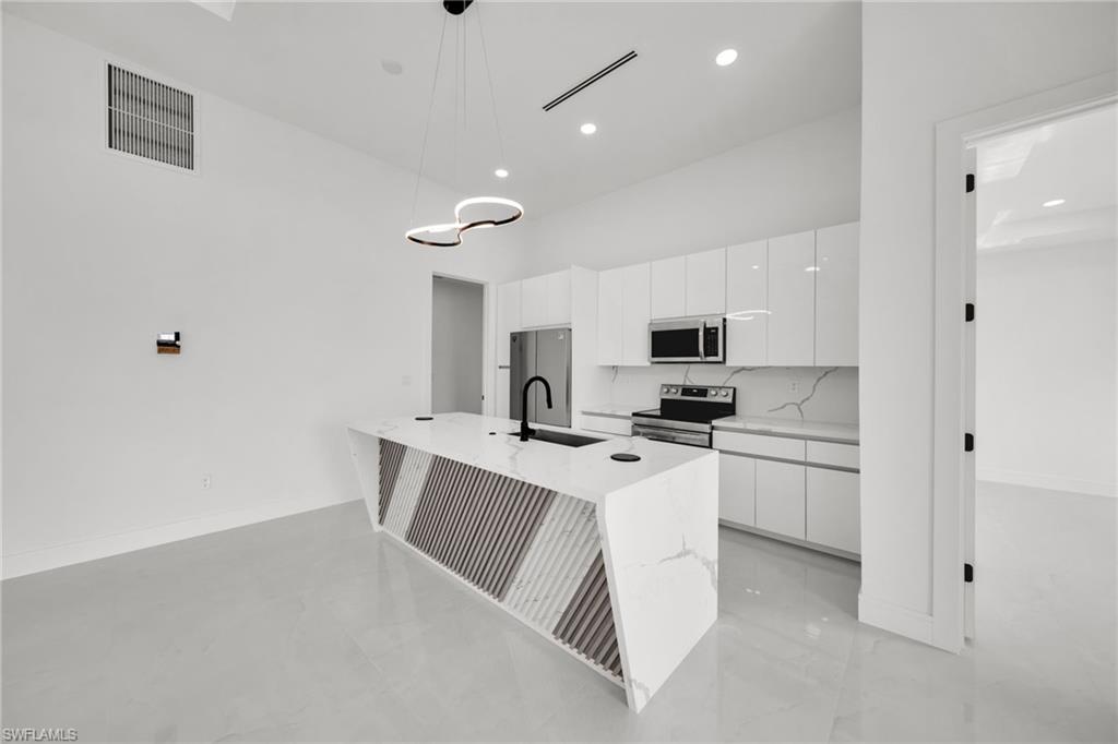 Contemporary kitchen featuring a waterfall island with a unique geometric design, high-gloss white cabinetry, and integrated stainless steel appliances
