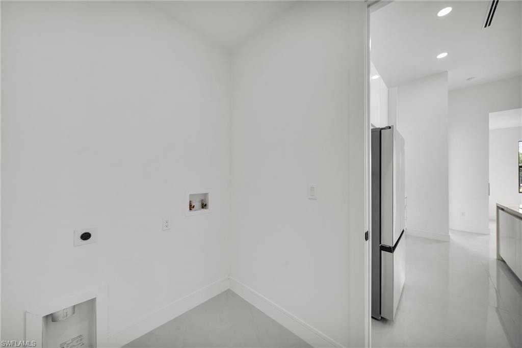 Dedicated laundry area featuring water hookups and drainage, with a nearby stainless steel refrigerator and recessed lighting