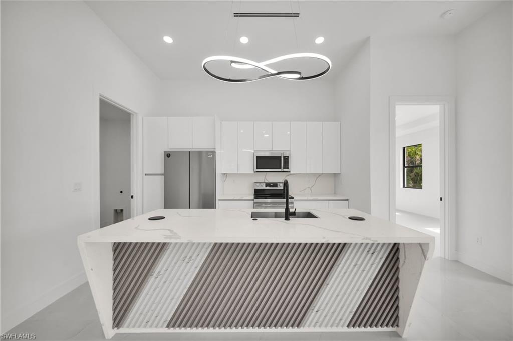 Kitchen island featuring a waterfall countertop with integrated sink and modern geometric paneling