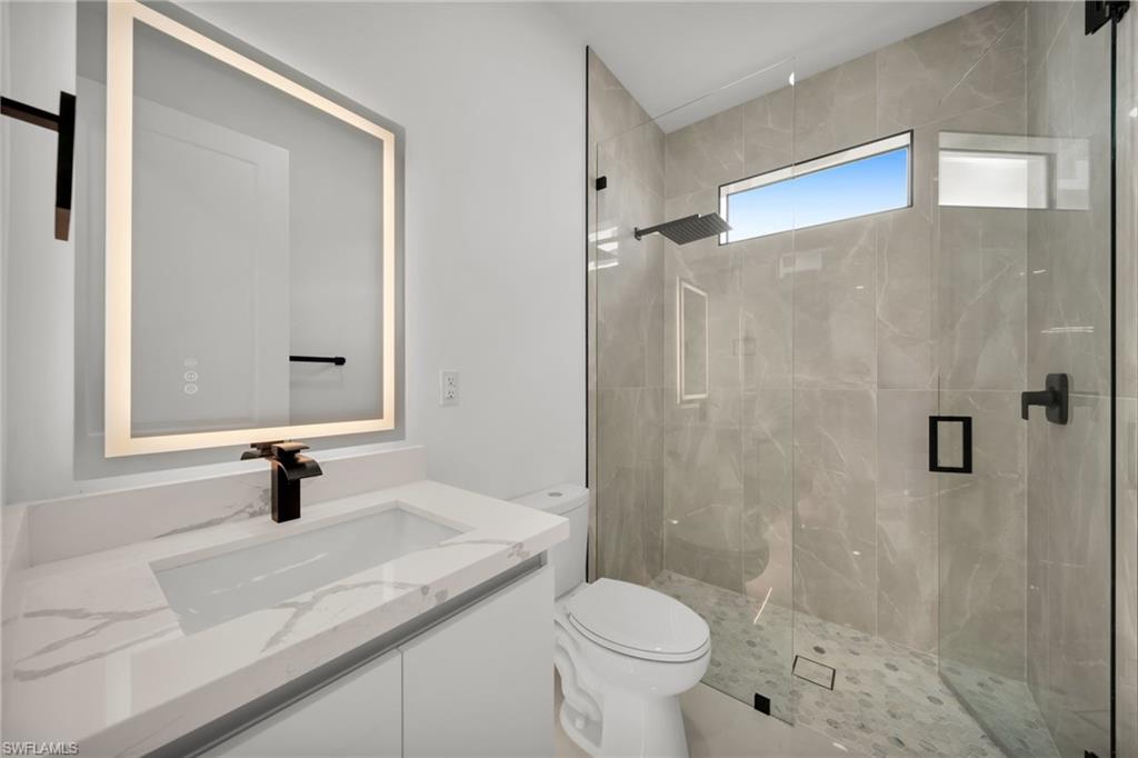 Modern bathroom featuring a frameless glass shower enclosure with a rain shower head and a horizontal window