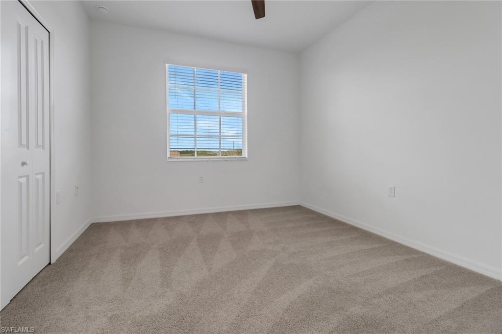 Bright room featuring a window with horizontal blinds, neutral-toned carpeting, a ceiling fan, and a white bi-fold closet door