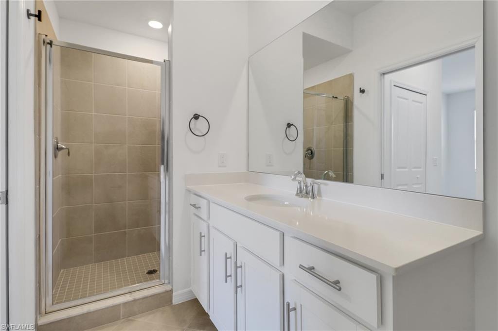 Bathroom featuring a glass-enclosed shower with tiled walls and floor, a single vanity with a white countertop, and a large wall-mounted mirror