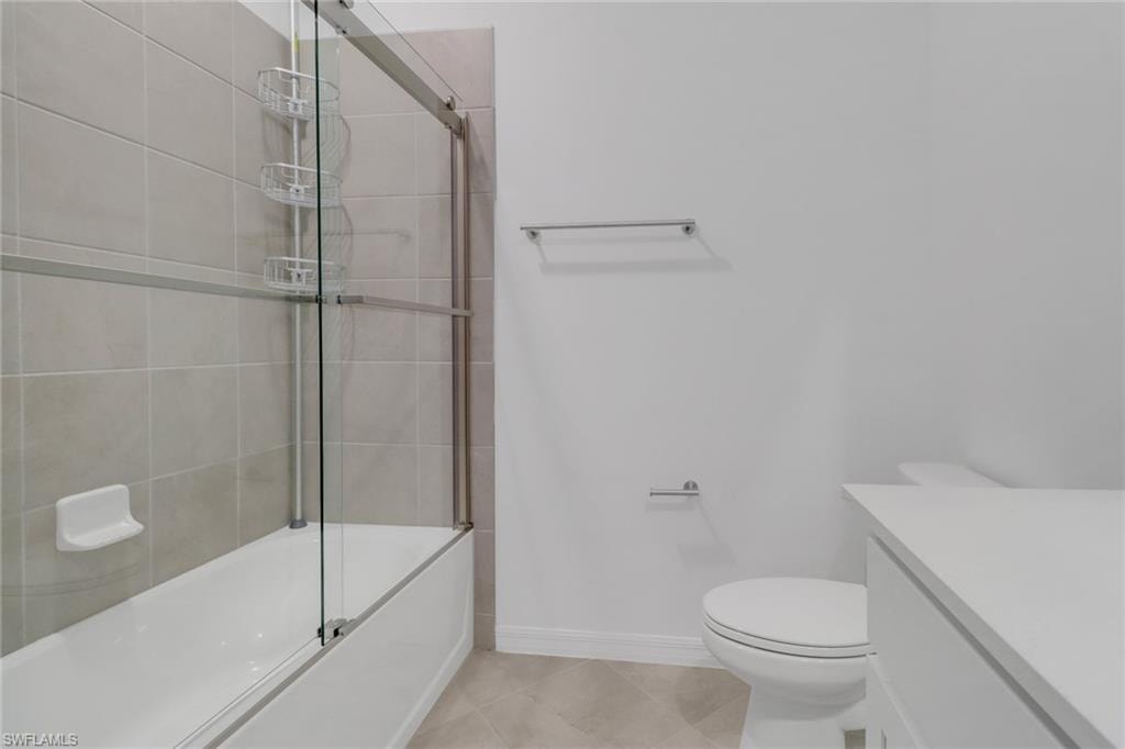 Bathroom featuring a shower/tub combination with sliding glass doors, light-toned tile surround, and an integrated soap dish