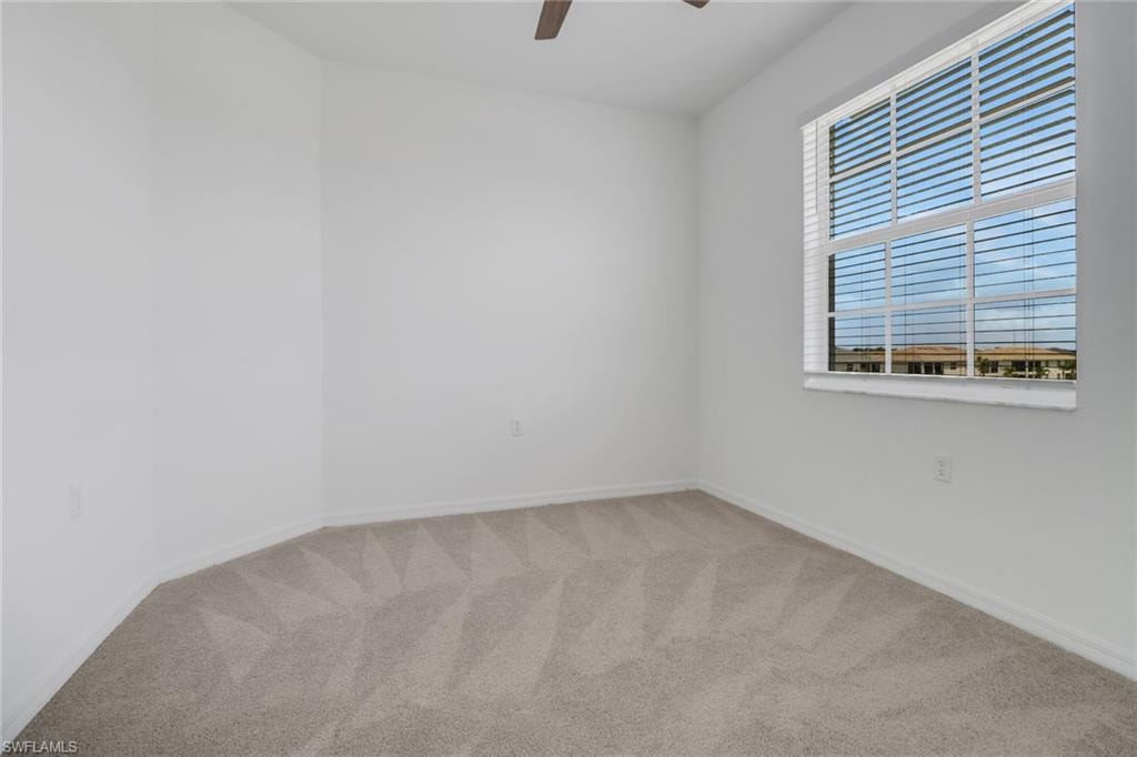 Bright room featuring a large window with horizontal blinds, neutral carpet flooring, and a ceiling fan