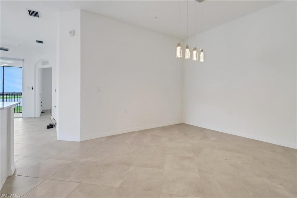Open concept living space featuring light-toned tile flooring, recessed lighting, and a contemporary linear chandelier with four individual glass pendants