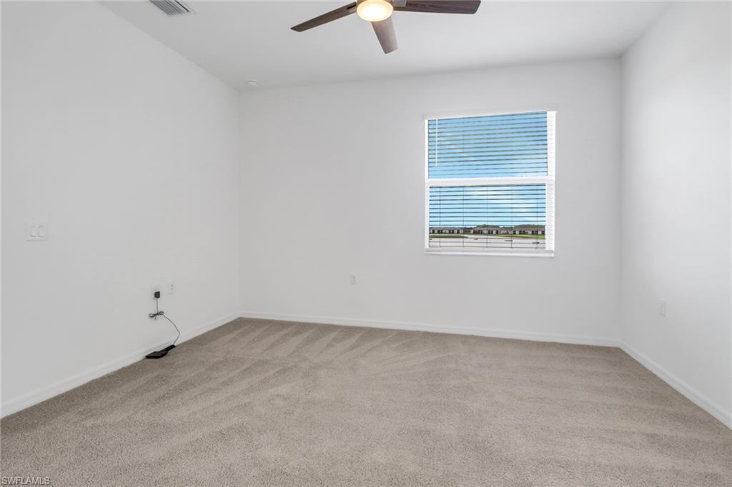 Spacious room featuring neutral carpeting, a large window with horizontal blinds, and a ceiling fan with integrated lighting