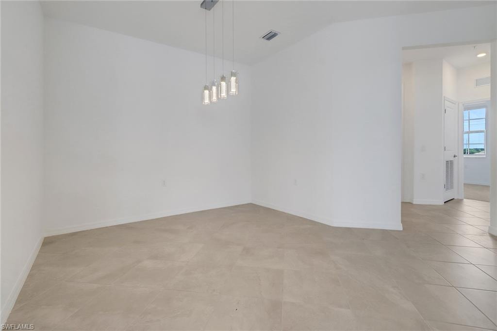 Spacious room featuring light-toned tile flooring, neutral wall tones, and a contemporary multi-light pendant fixture