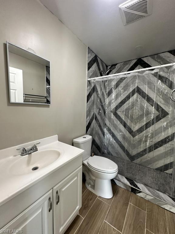 Bathroom with vanity, a shower stall, and wood tiled floors