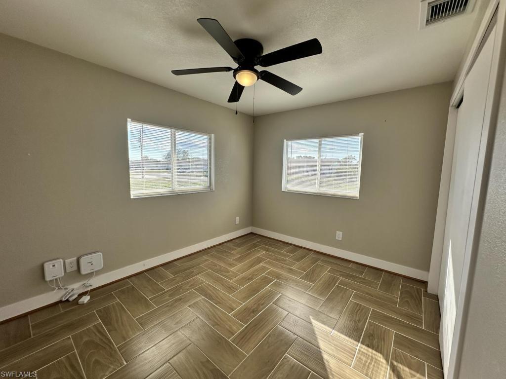 Unfurnished bedroom featuring ceiling fan, multiple windows, and parquet flooring