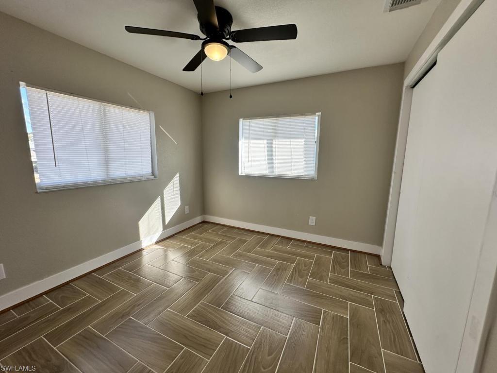 Unfurnished bedroom with ceiling fan, parquet floors, and a closet