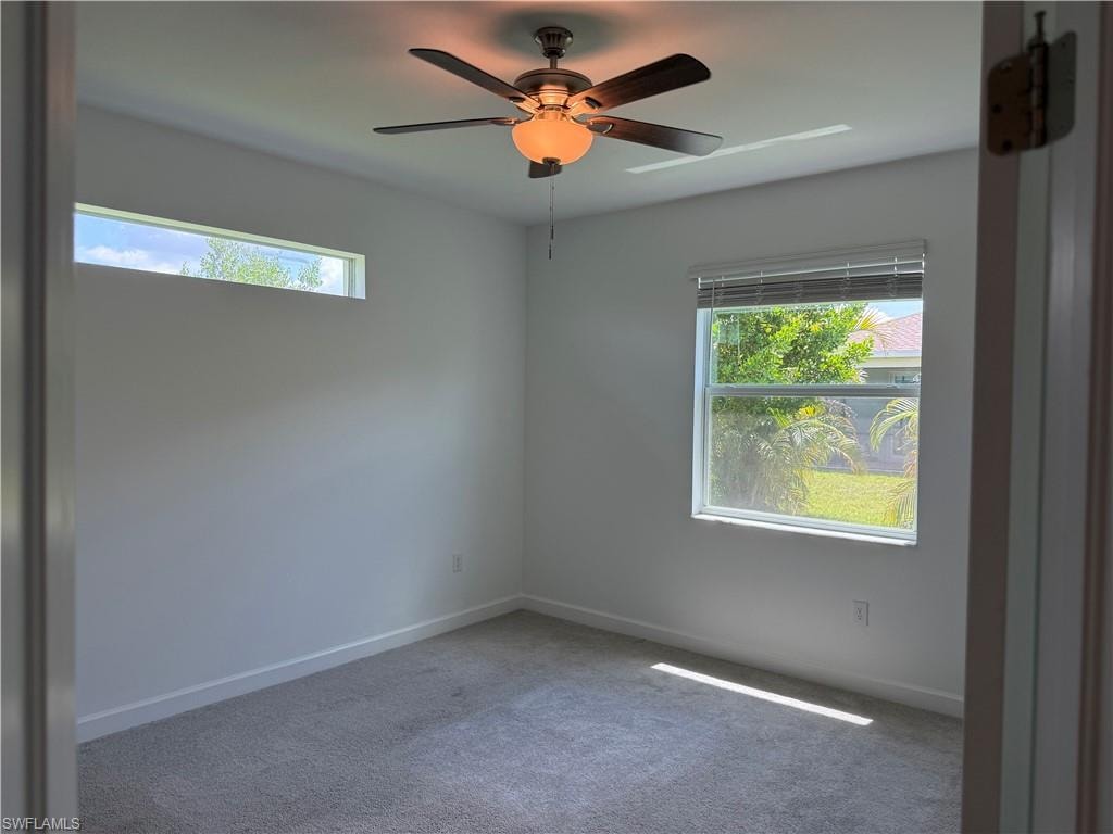 Carpeted room featuring a ceiling fan with integrated lighting, a horizontal clerestory window, and a standard window with blinds