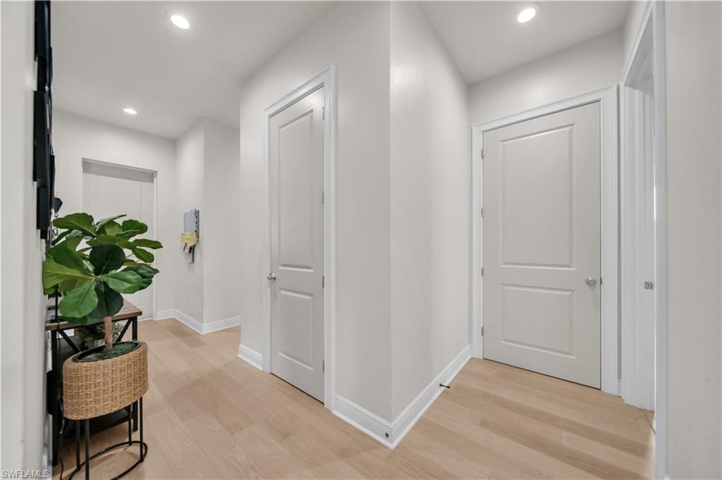 Bright hallway featuring light wood-finish flooring and recessed lighting