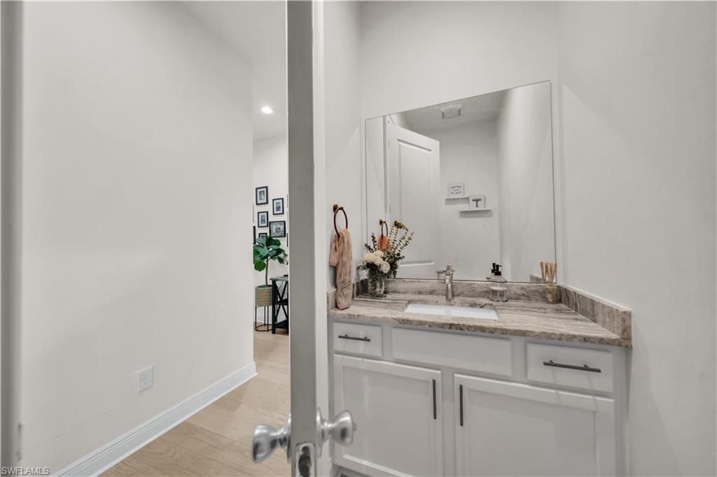 Vanity area featuring a rectangular undermount sink, a polished chrome faucet, and a stone-finish countertop