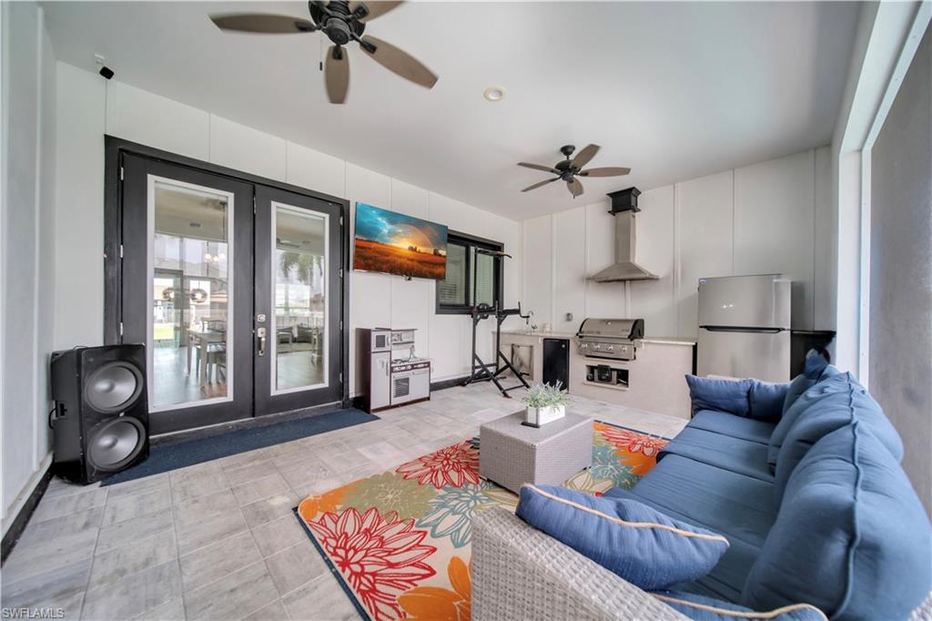 Covered patio featuring an outdoor kitchen with built-in grill, stainless steel refrigerator, and range hood