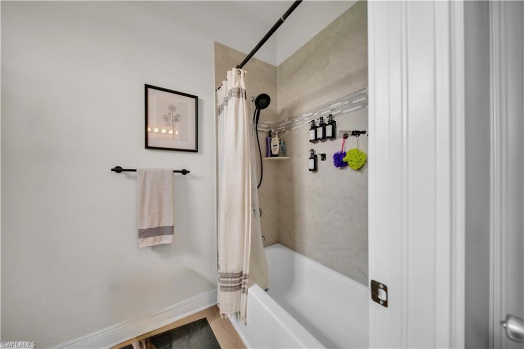 (Guest Bathroom)  White soaking tub with tiled surround, featuring a shower head with handheld sprayer