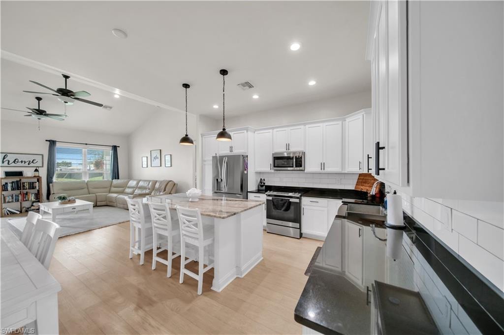 Modern kitchen featuring white cabinetry, black countertops, and a white subway tile backsplash