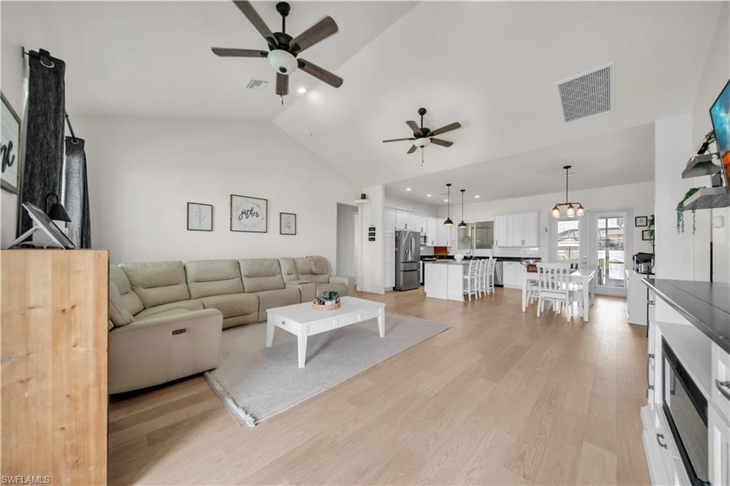 Open-concept living space featuring wood-finish flooring, vaulted ceilings, and ceiling fans