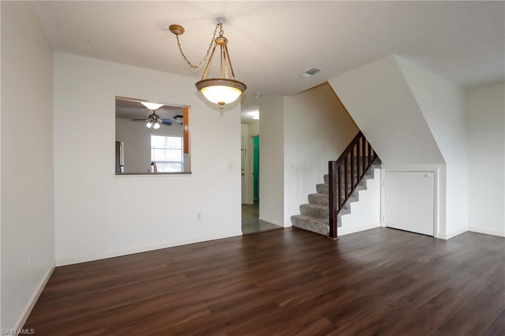 Unfurnished living room featuring dark wood finished floors, stairway, and a ceiling fan