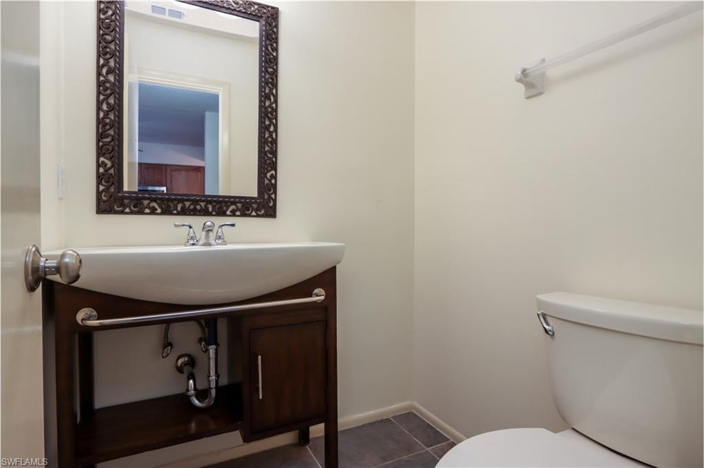 Half bath with tile patterned floors and vanity