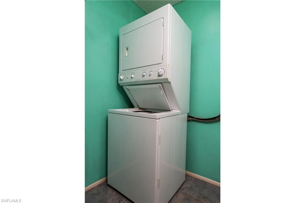 Washroom featuring stacked washer / drying machine and baseboards