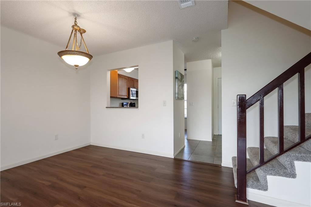 Unfurnished room with dark wood-type flooring, stairway, and a textured ceiling