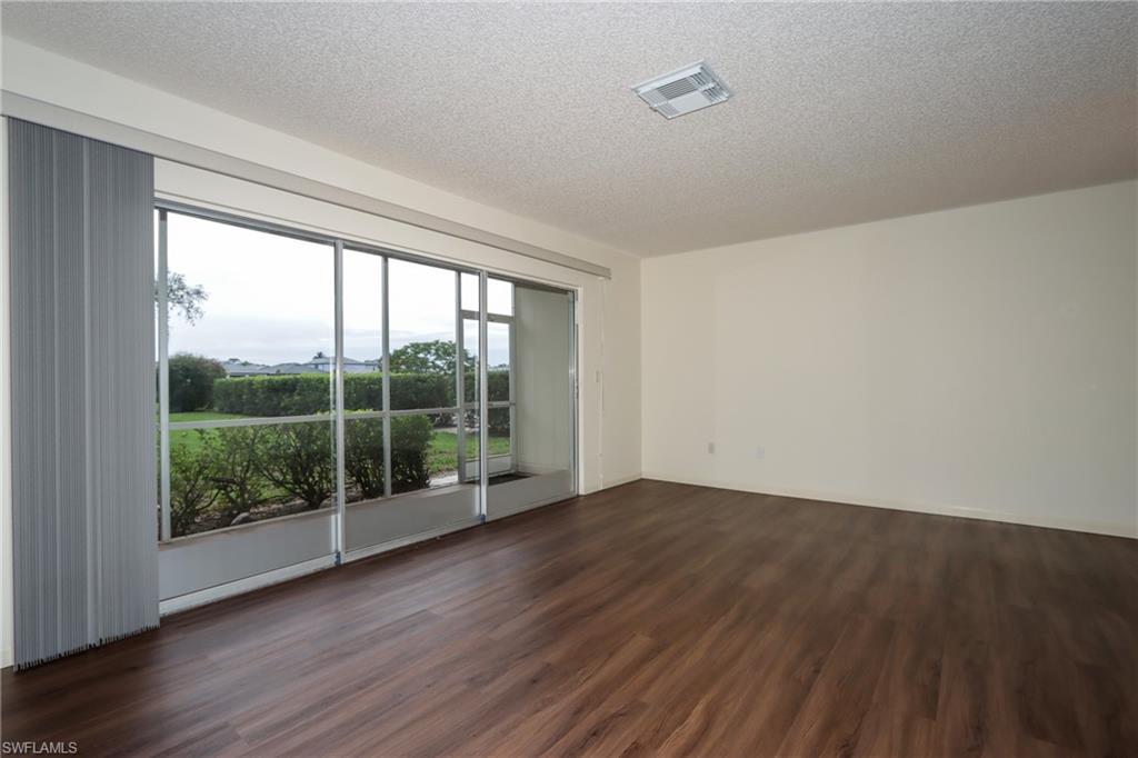 Unfurnished room featuring dark wood-type flooring and a textured ceiling