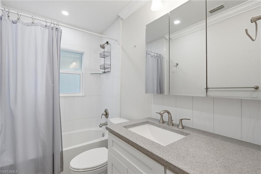 Full bathroom featuring a white vanity cabinet with a speckled countertop, an undermount sink, and brushed nickel fixtures