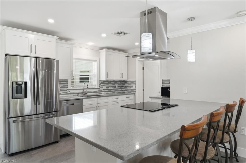 Modern kitchen featuring white shaker cabinetry, stainless steel appliances, and an expansive island with a built-in Glass top range and hood.