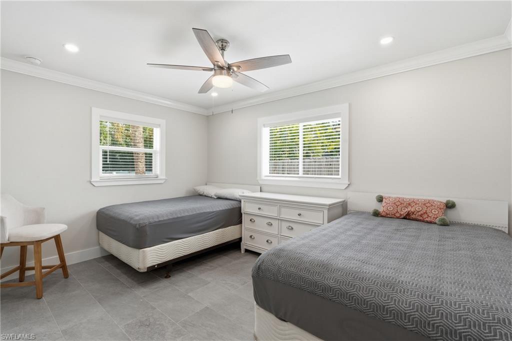 Modern bedroom featuring light gray walls, gray tile flooring, and white crown molding