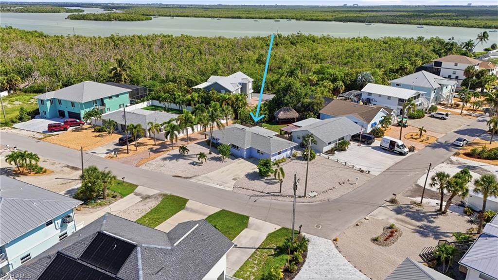 Waterfront property featuring a tropical landscape, mature palm trees, and a gravel yard.