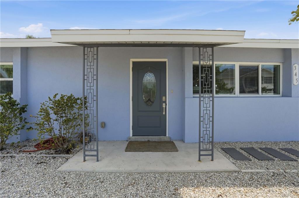 Front entry featuring a covered porch with decorative metal columns, a dark gray oval-lite door.