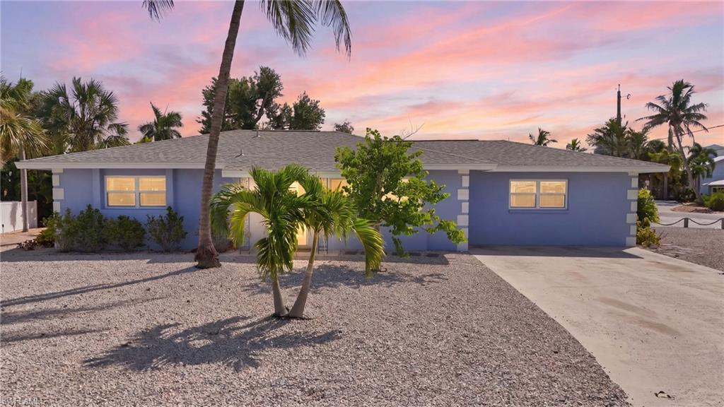 Ranch-style residence featuring a pale blue exterior with white trim accents and a gray shingled roof