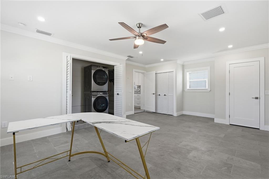 Spacious room featuring gray plank tile flooring, recessed lighting, a ceiling fan with wood-finish blades, and a dedicated laundry closet with stacked appliances.