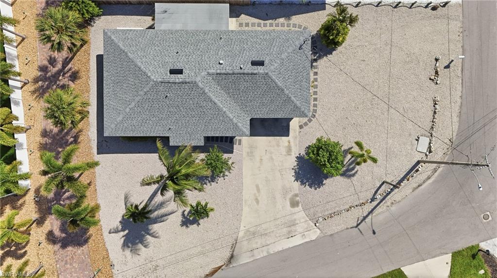 Gabled roof structure with a shingle finish, complemented by a concrete driveway and an unpaved yard