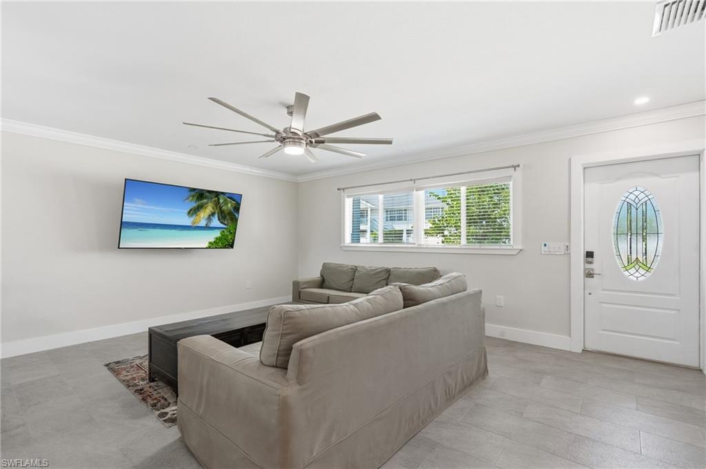 Living area featuring light gray wall paint, crown molding, and wood-finish tile flooring