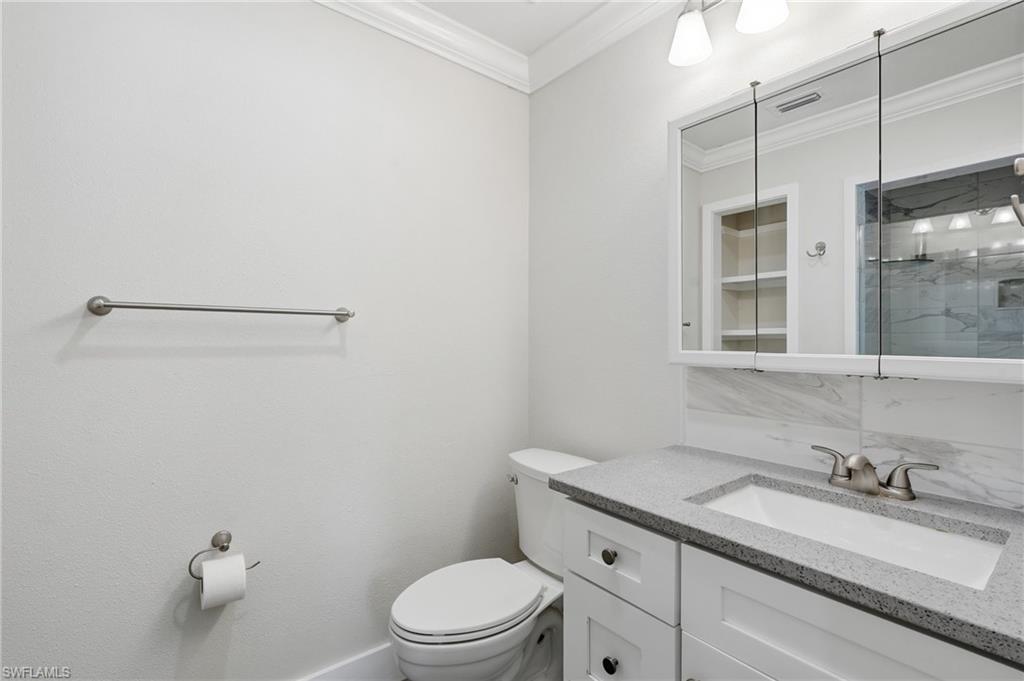 Bathroom vanity featuring a light-colored countertop, undermount sink, and shaker-style cabinetry with dark hardware