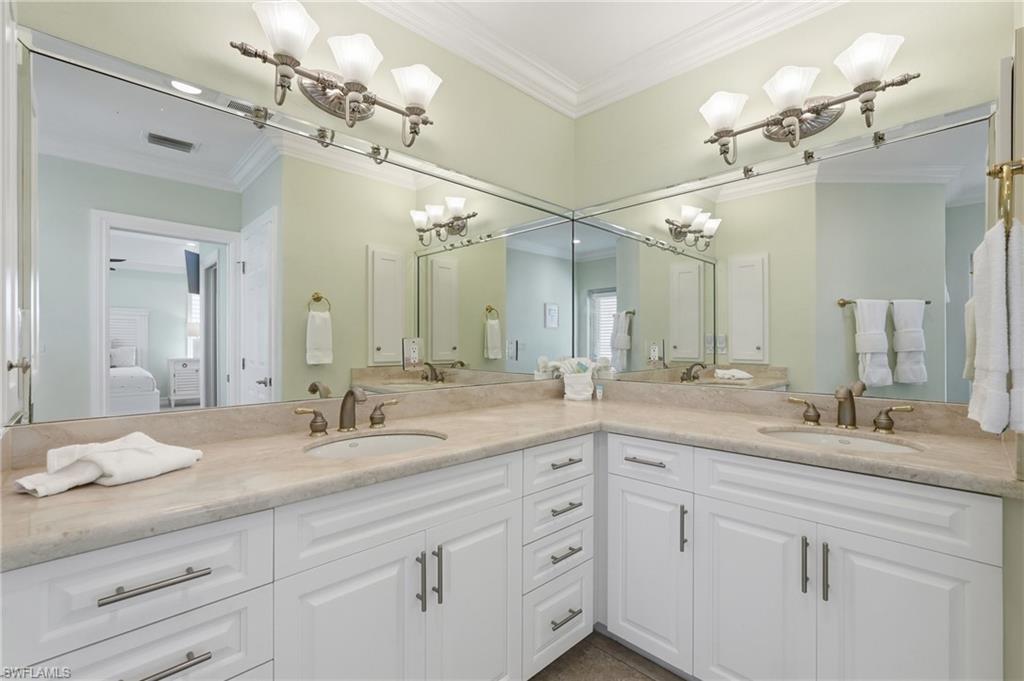 Dual vanity with individual sinks, extensive countertop space, white cabinetry, integrated mirrors, and decorative light fixtures - Virtually Edited Image