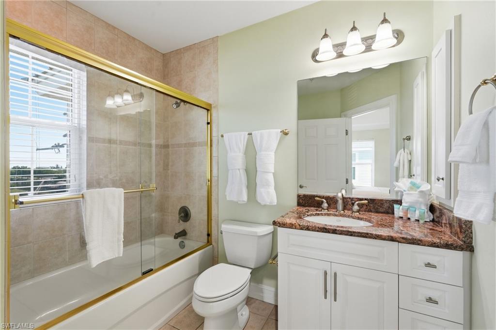 Bathroom featuring a vanity with a dark marble-finish countertop, single basin sink, and white cabinetry - Virtually Edited Image