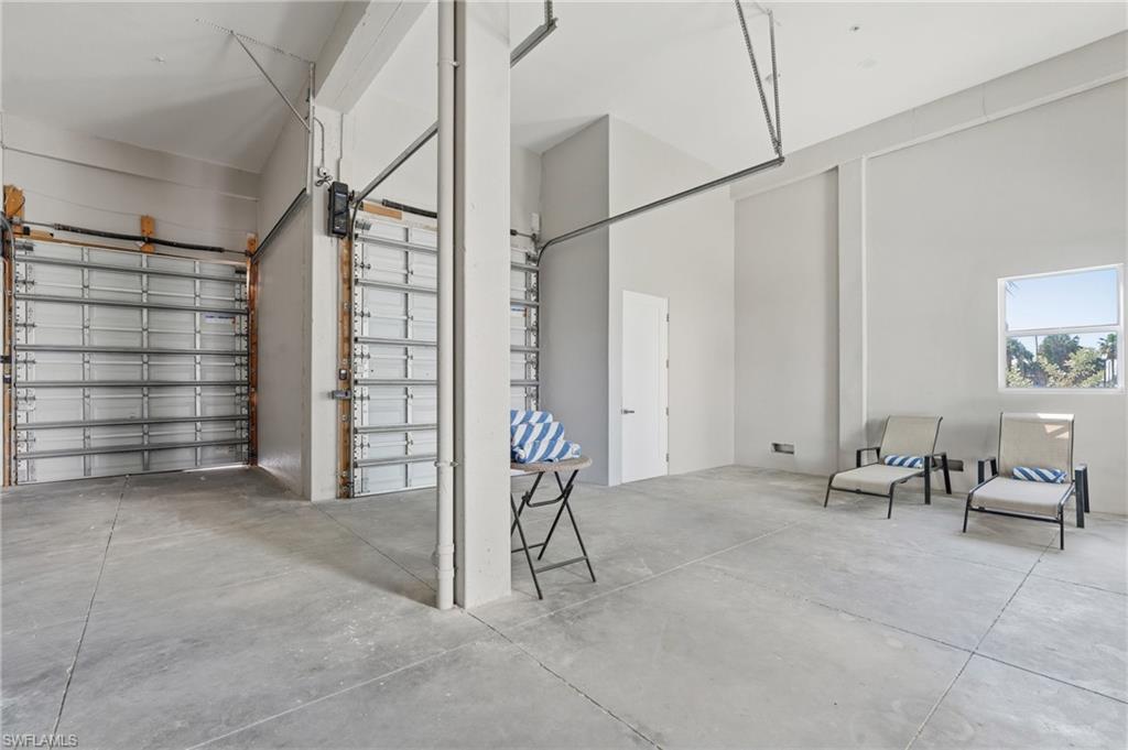 Spacious interior with high ceilings, concrete flooring, and multiple roll-up garage doors - Virtually Edited Image