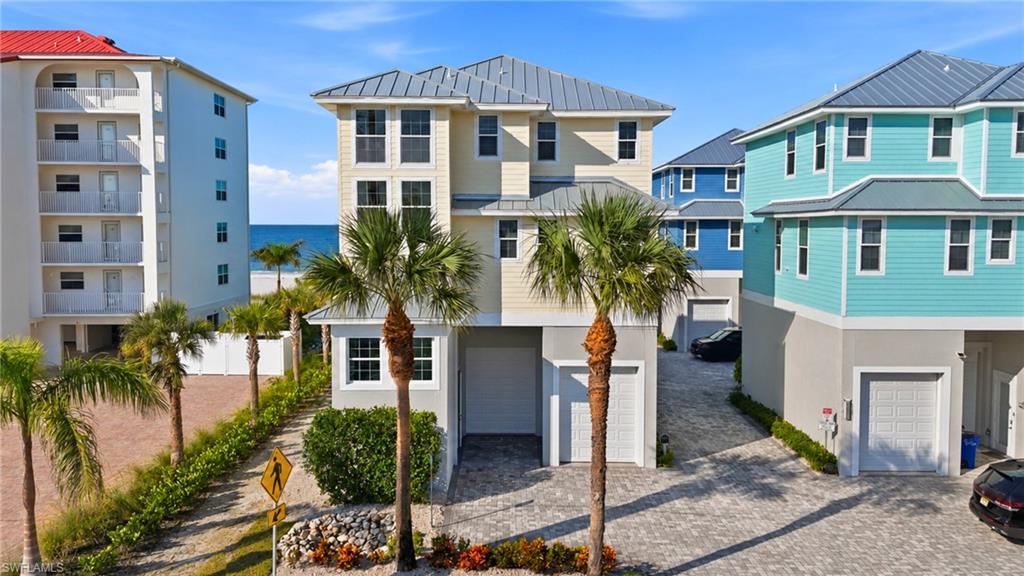 Modern coastal residence featuring a striking cream and black exterior with metal roof accents, flanked by mature palm trees - Virtually Edited Image